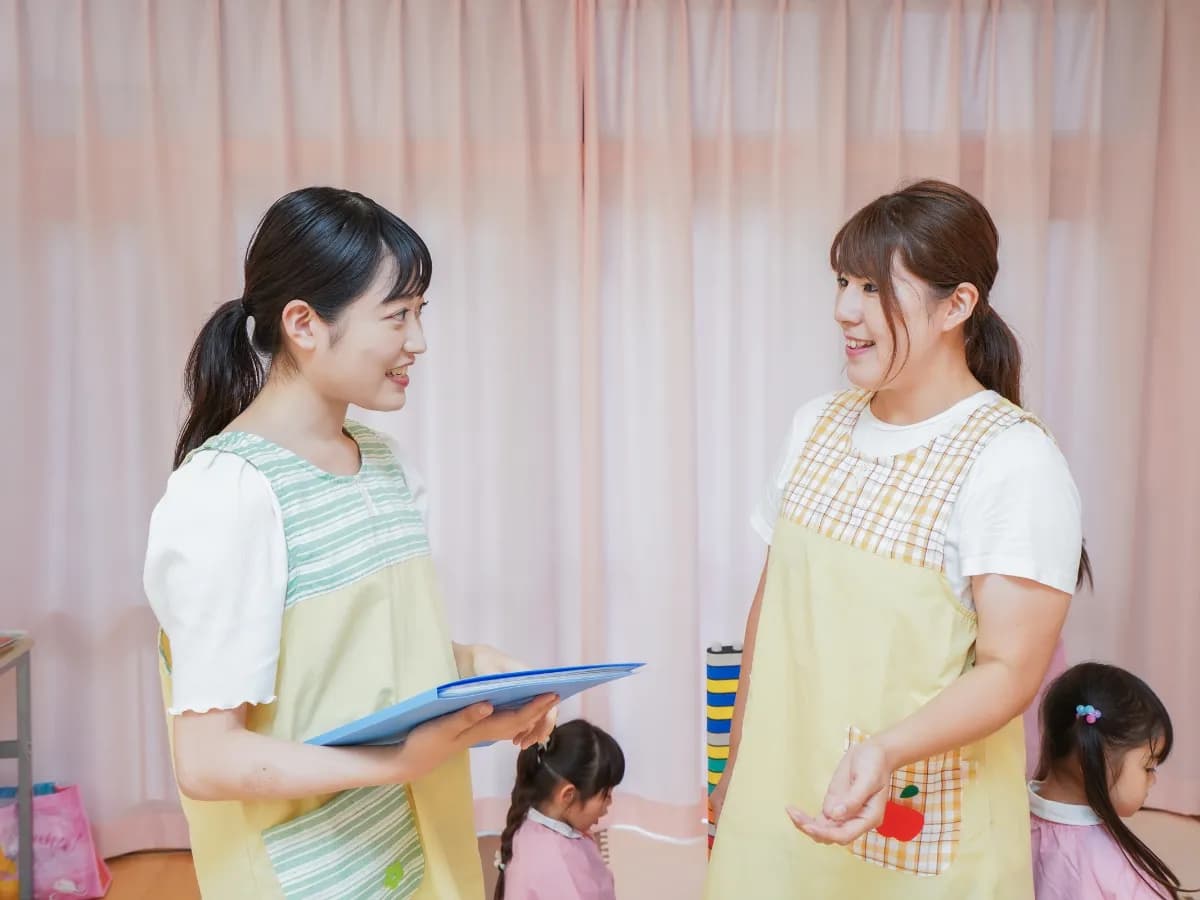 業務の引継ぎをしている二人の女性保育士のイメージ