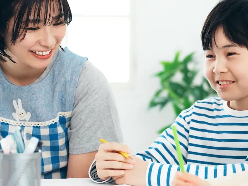勉強している男児を見守る女性の画像