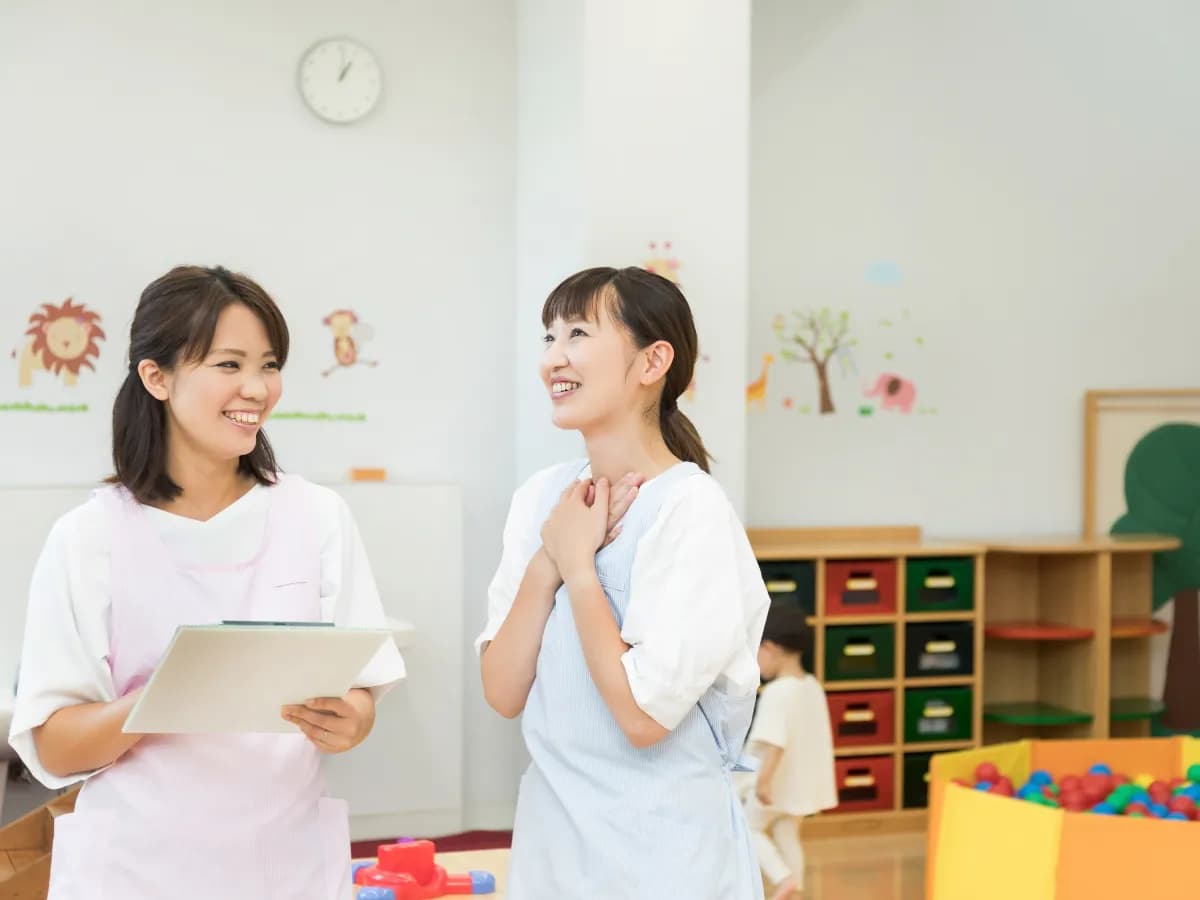 書類を持った保育士と笑顔で会話する保育士の画像