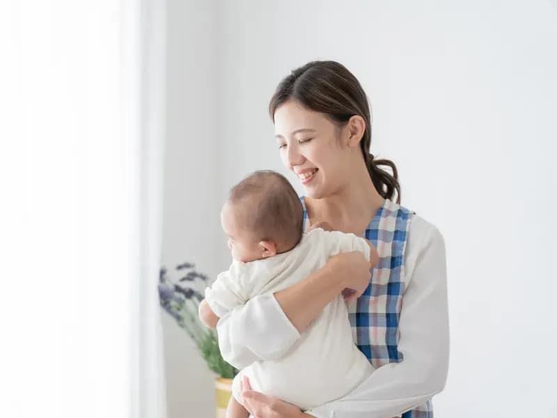 乳児を抱っこする保育士の画像