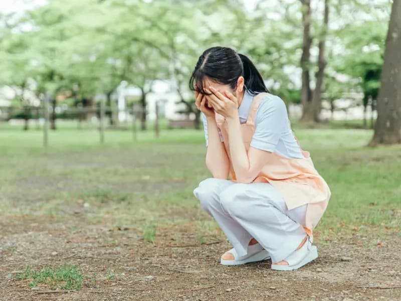 うずくまって頭を抱える保育士の画像