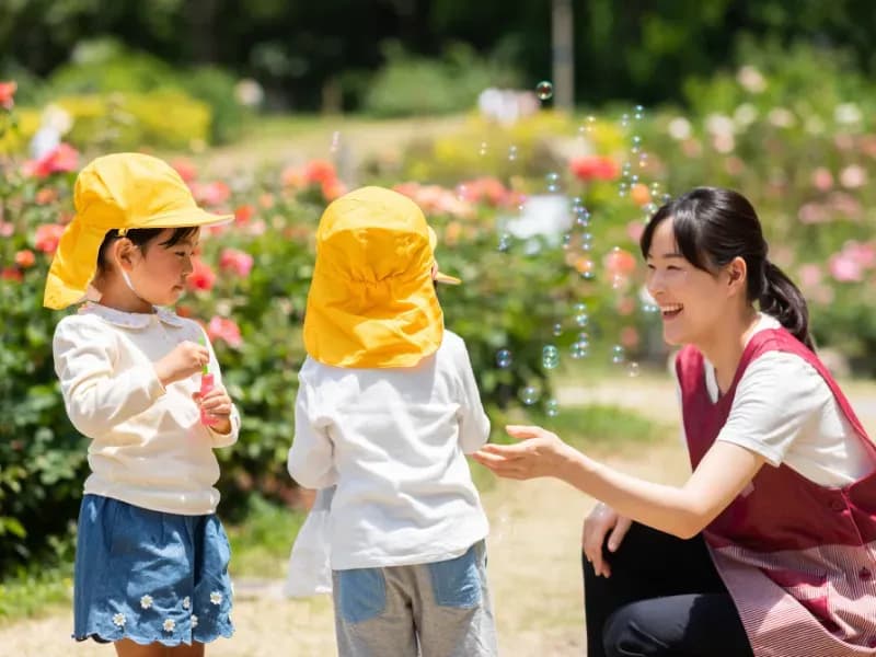 公園で遊ぶ保育士と園児たちの画像