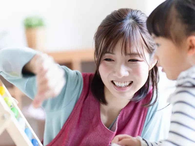 遊具で遊ぶ保育士と園児の画像