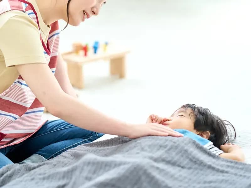 寝かしつけをする保育士のイメージ