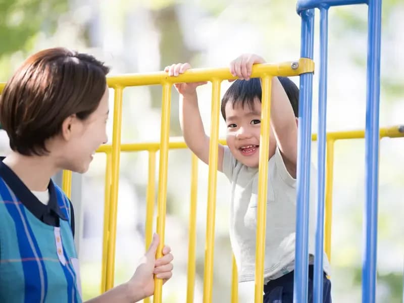 遊具で遊ぶかわいい笑顔の保育園児と保育士のイメージ