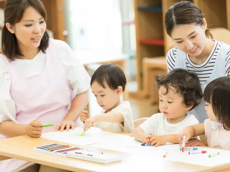 絵を書いてる子供と見守る保育士のイメージ