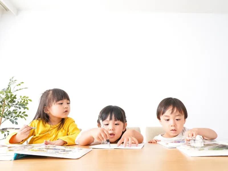 本を見ながら勉強をしている幼児たちの画像