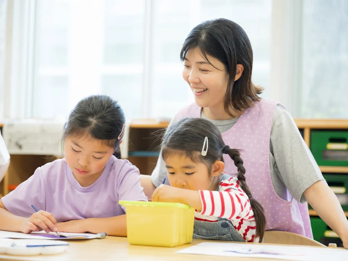 笑顔で子供たちの制作を見守る支援員のイメージ
