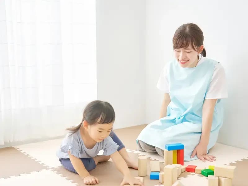 積み木をする児童と見守る先生の画像