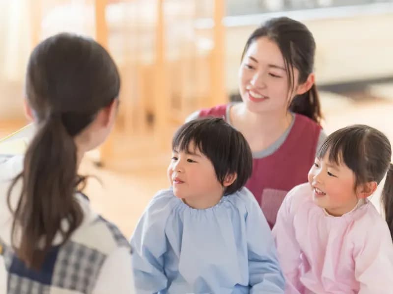 読み聞かせをする保育士と保育補助のイメージ