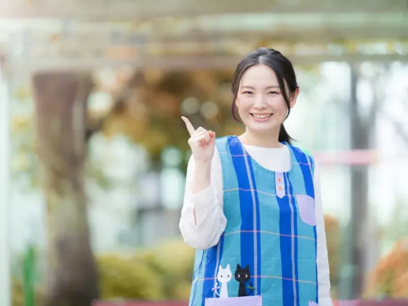 保育士が人差し指を立ててほほ笑んでいる画像