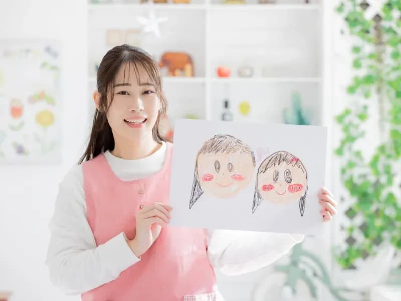 似顔絵を持つ保育士のイメージ