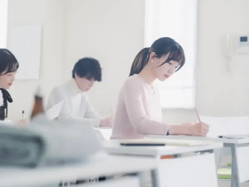 試験会場で試験を受ける人たちの画像