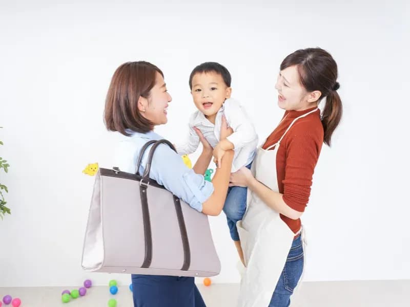 お迎えに来た保護者と迎えを待つ園児と先生の画像