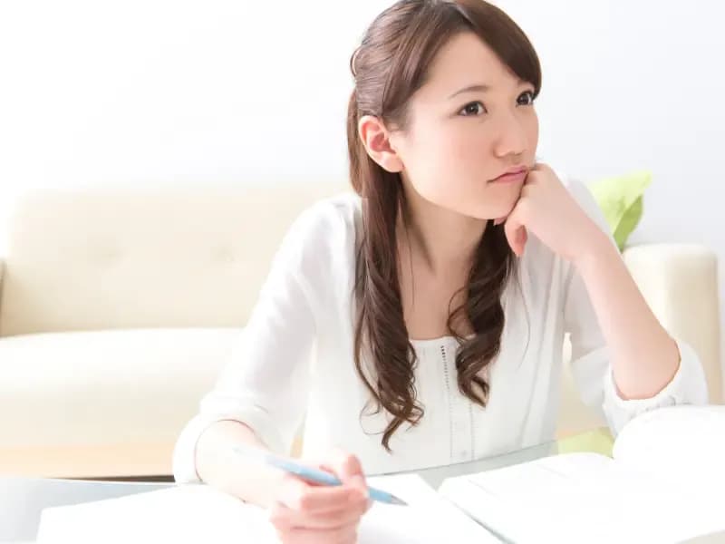 勉強をしながら考え事をする女性のイメージ