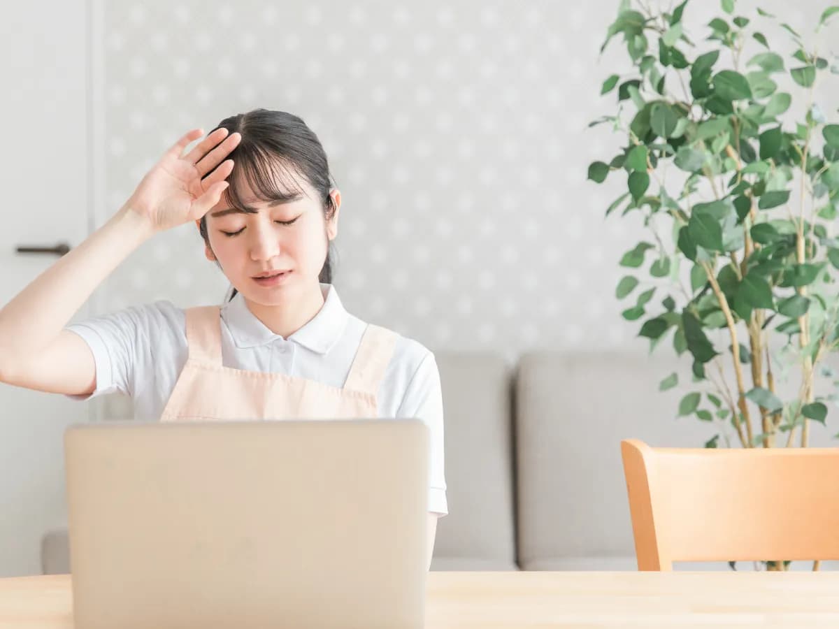 パソコンを前に疲労を感じている女性保育士のイメージ