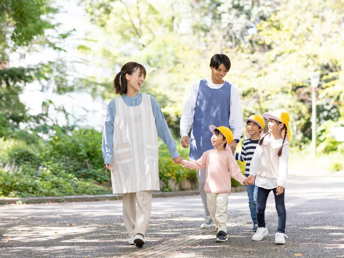子供と散歩している男女の保育士の画像