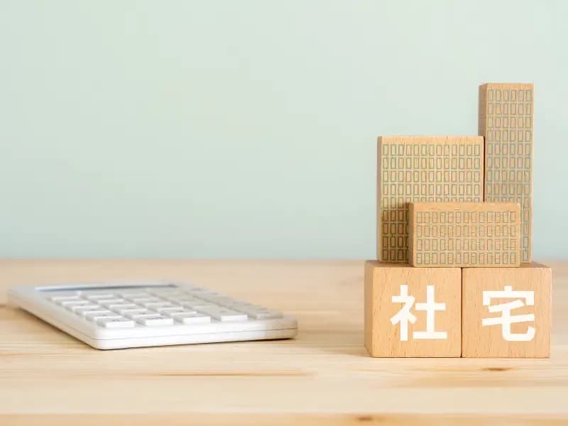 社宅と書かれたブロック、電卓、ミニチュアの建物のイメージ
