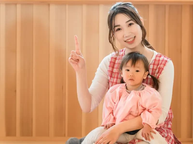 幼児の女の子を抱っこする保育士の画像