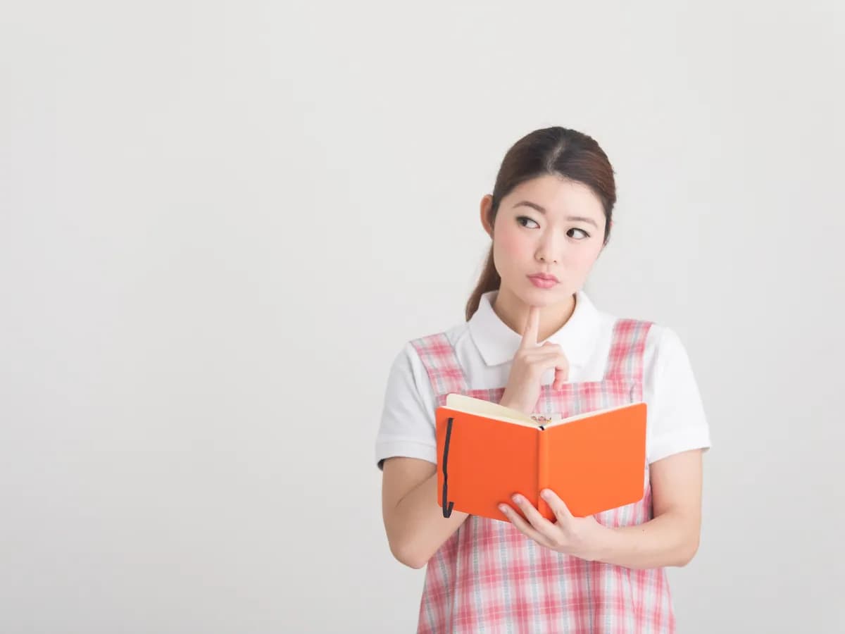 スケジュール帳を開き考える保育士のイメージ