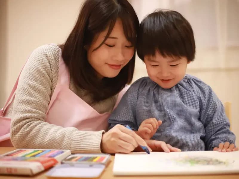 お絵描きする男の子と幼稚園教諭のイメージ