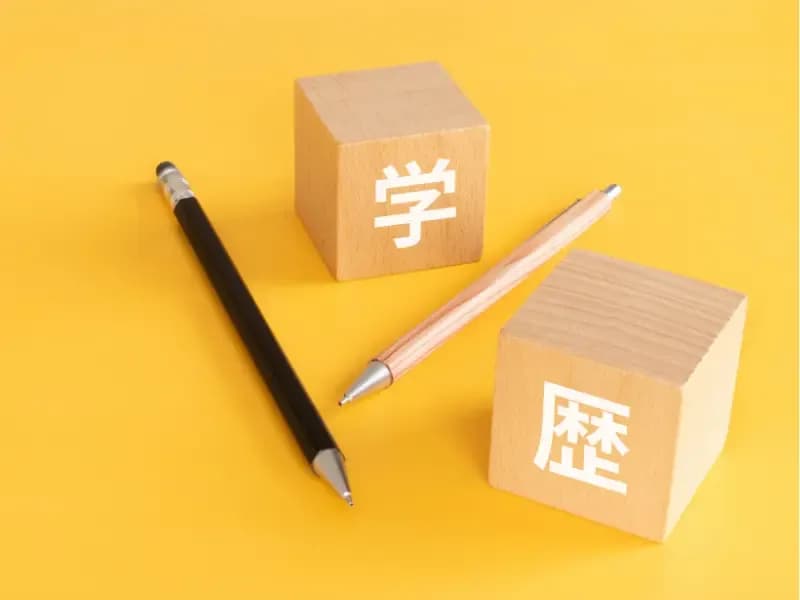 学歴と書かれた積み木とペンの画像