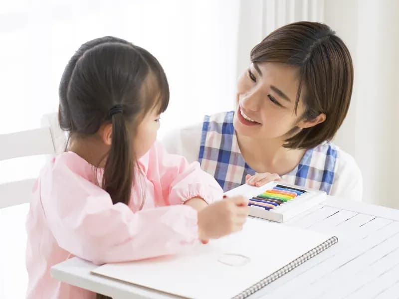 お絵描きをする園児と見守る幼稚園教諭の画像