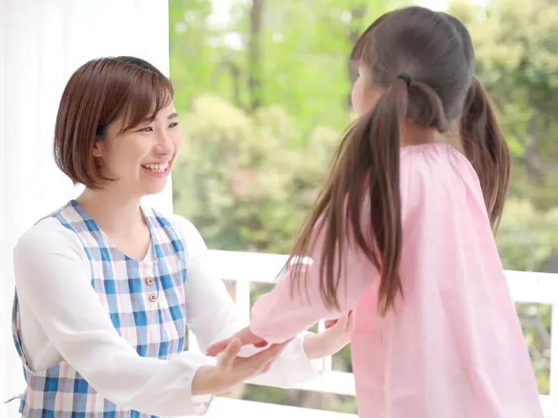 手をつなぐ保育士と園児の画像