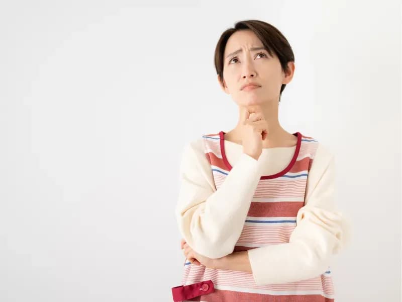 困った顔で考える保育士の画像