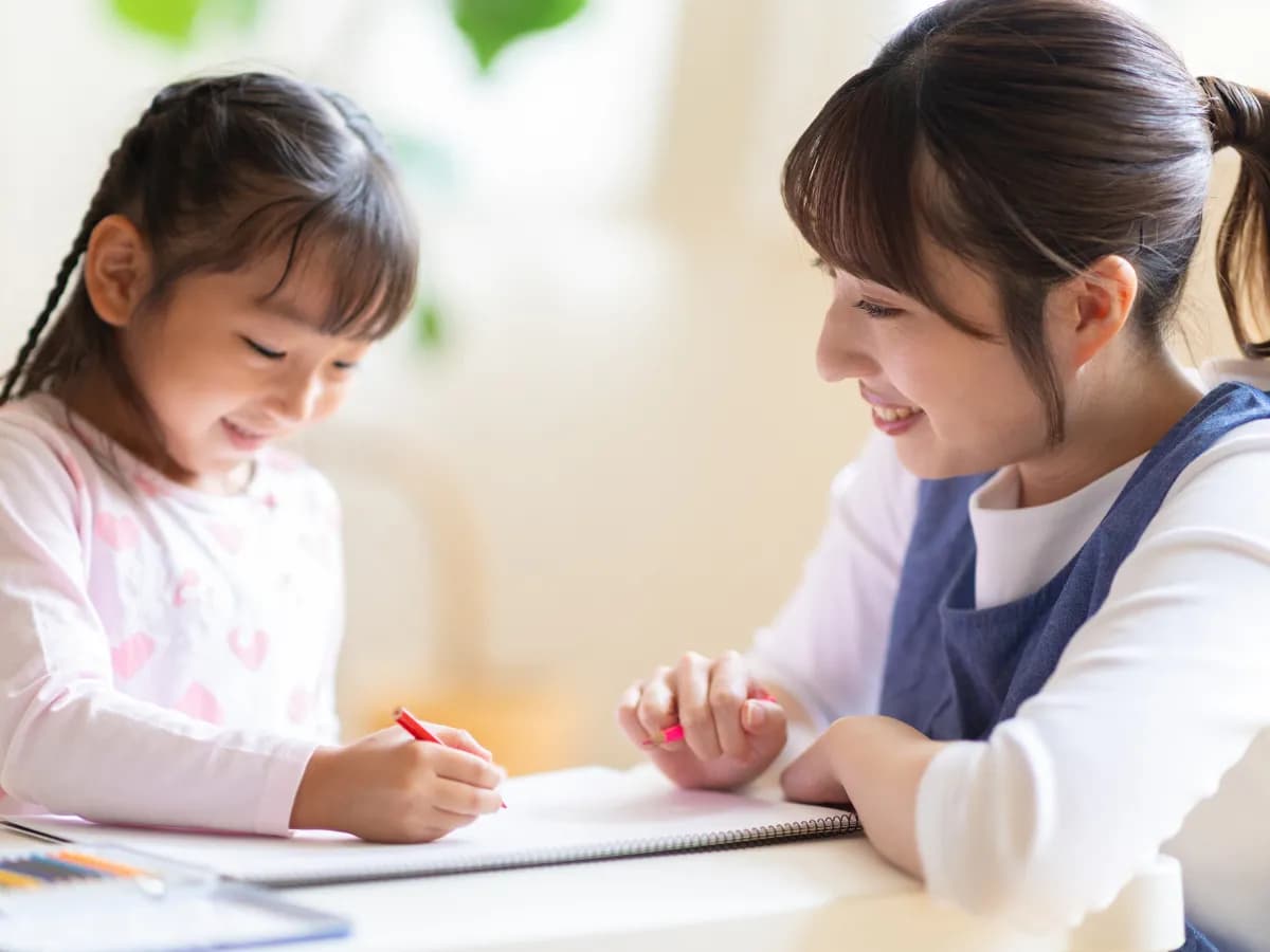 園児と絵を描いている保育士のイメージ