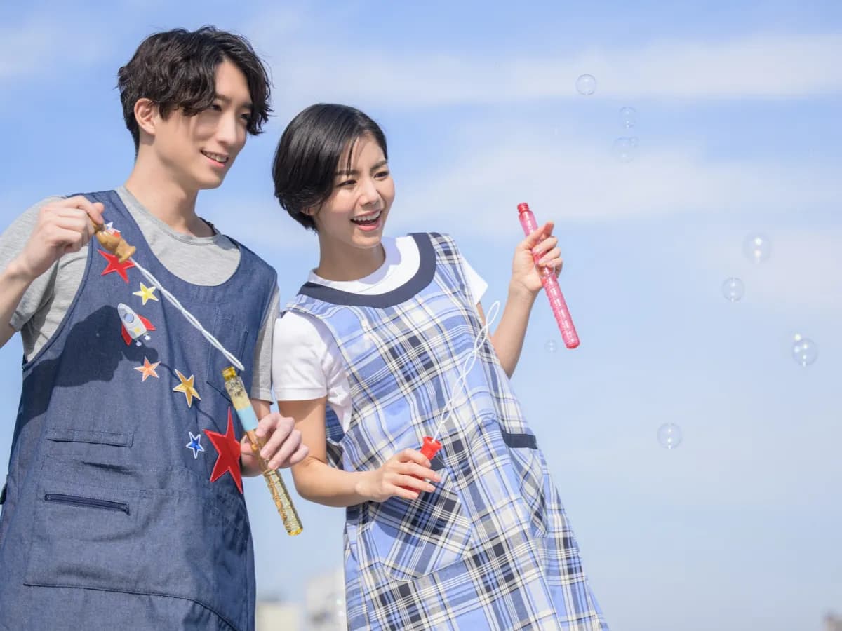 シャボン玉をする男女の保育士の画像