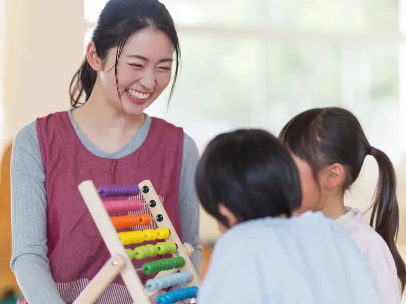 幼稚園児の活動を見守る幼稚園教諭の画像